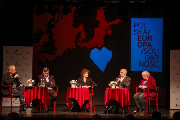 Oświetlona scena (Teatr Polski w Szczecinie, Nowy Browar), przy stolikach siedzi pięć osób - uczestników debaty "Ulica i zagranica - pomoc dla Solidarności". Na pierwszym planie widać publiczność.