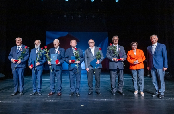Spotkanie z kombatantami i opozycjionistami w Teatrze Polskim w Szczecinie. Na scenie Przewodnicząca Sejmiku Województwa Teresa Kalina, Członek Zarządu Województwa Stanisław Wziątek i sześciu uhonorowanych odznakami mężczyzn w garniturach.