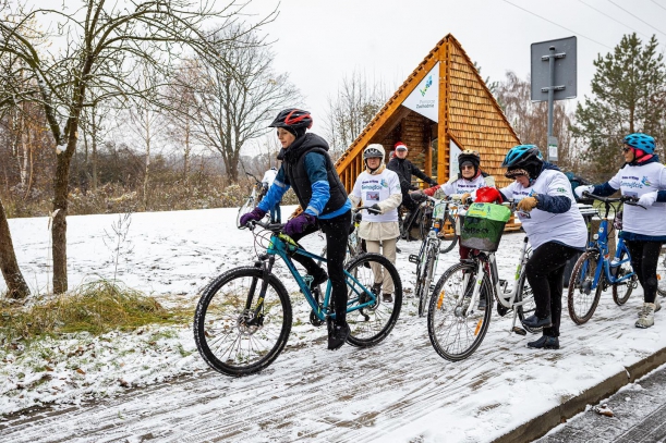 Rowerzyści na rowerach, w tle wiata. 