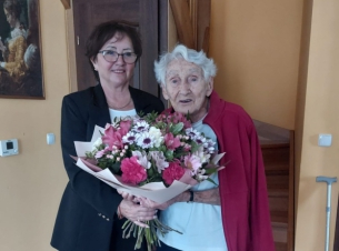 Przewodnicząca Sejmiku Województwa Zachodniopomorskiego Teresa Kalina pozuje do zdjęcia z panią Amelią Korycką, kombatantką, uczestniczką Powstania Warszawskiego. Wspólnie trzymają duży bukiet kwiatów. Wizyta odbyła się z okazji 97 urodzin pani Amelii.