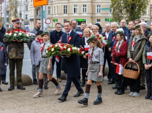 Uroczystość z okazji Narodowego Święta Niepodległości przy pomniku marszałka Józefa Piłsudskiego w Szczecinie. Grupa zgromadznych na placu Szarych Szergów. W śród nich marszałek województwa Olgierd Geblewicz z wiązanką białych i czerwonych kwiatów.
